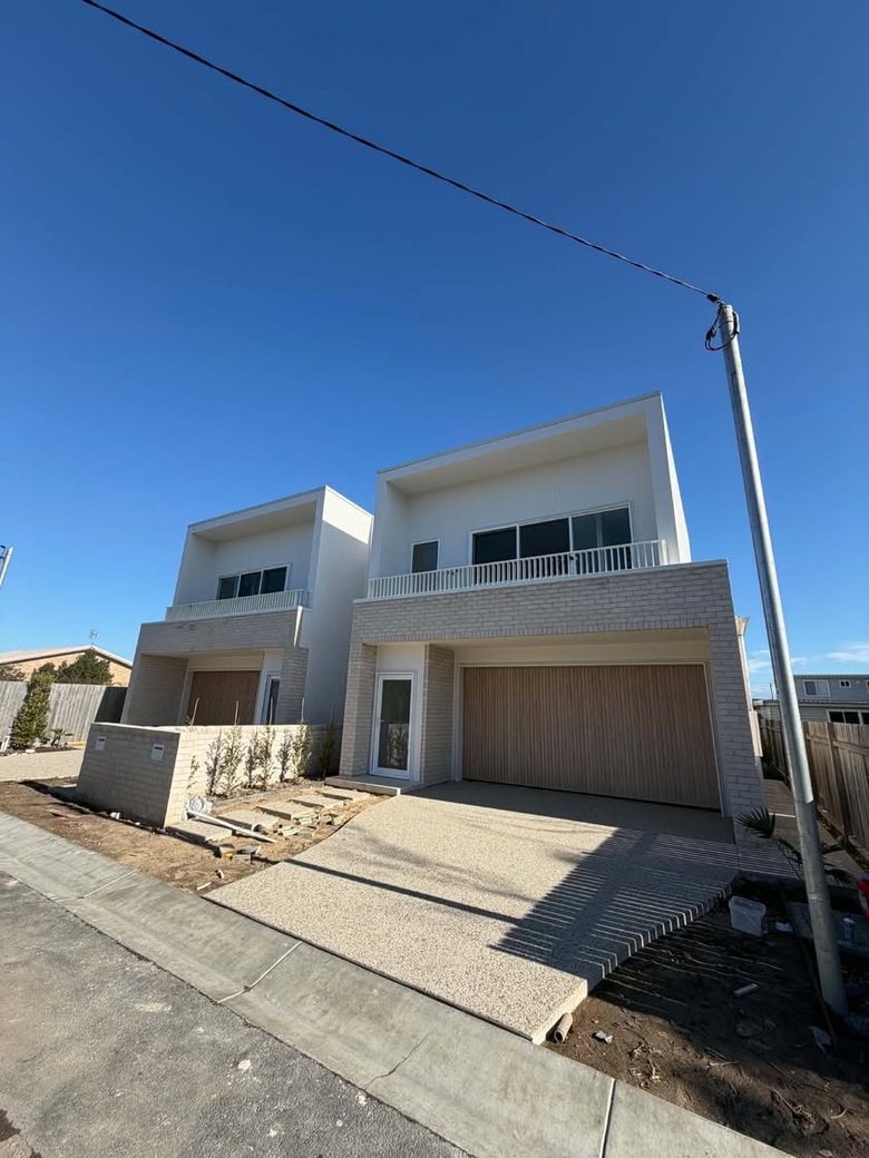White balustrades on the first-floor balconies of a pair of new two-storey townhouses.