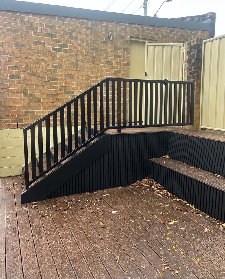Black powder-coated balustrade and matching stair rail on a timber deck.