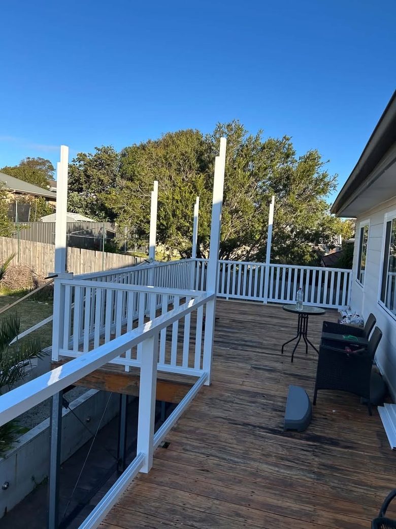 White balustrade being installed along a raised timber deck with posts set ready for the top rail.