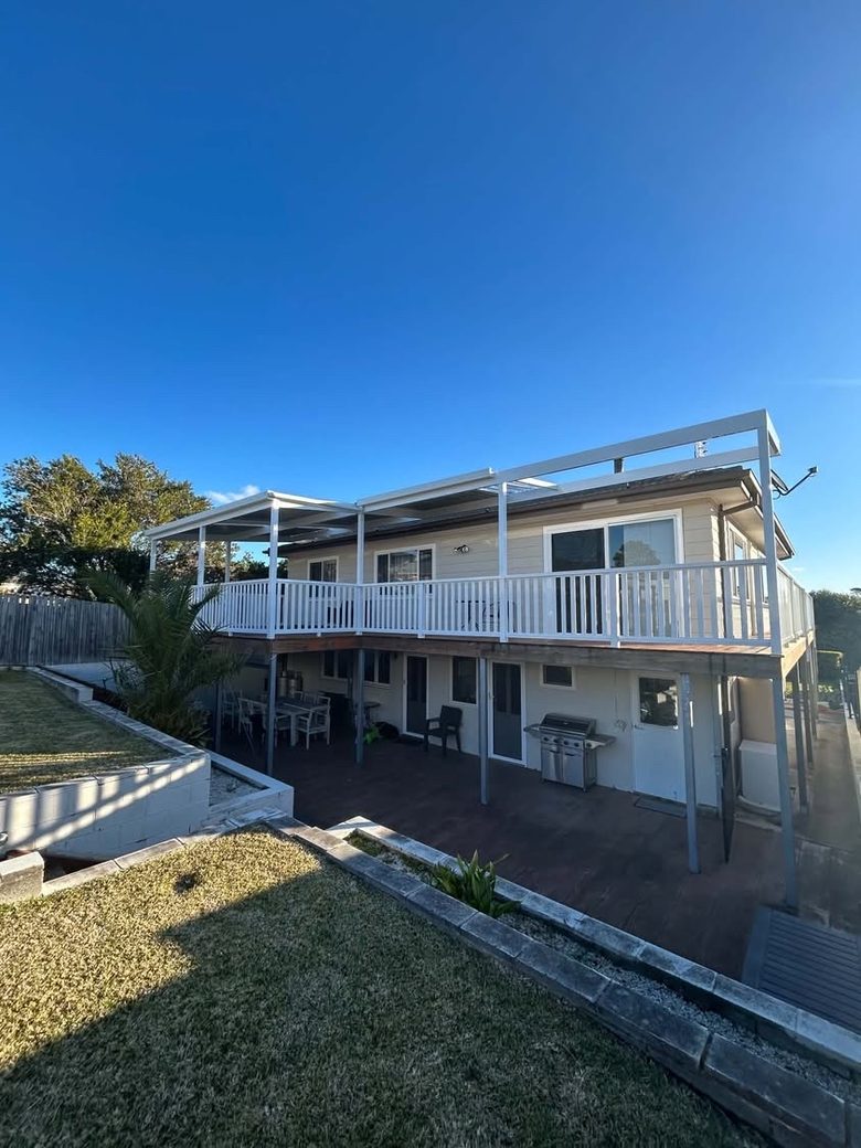 White deck balustrade running the full length of a raised verandah with an awning frame above.