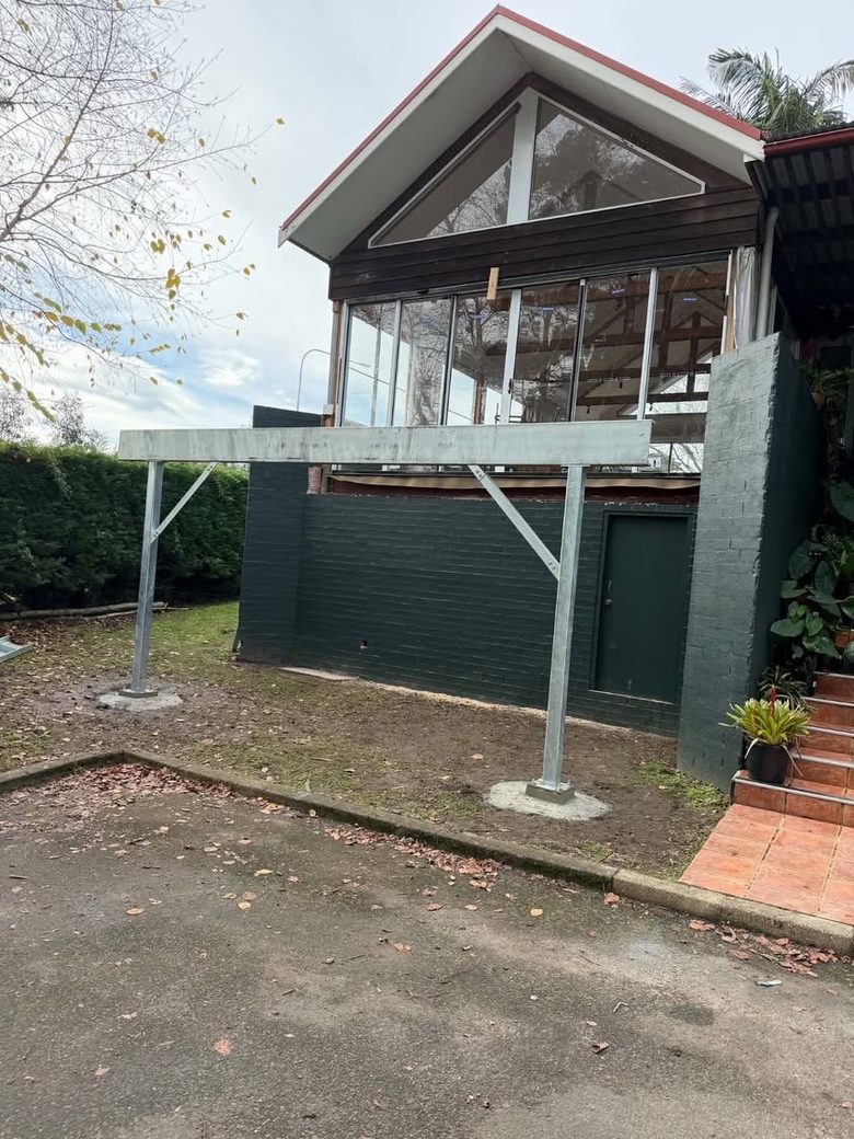 Galvanised steel subframe carrying a first-floor deck above a painted brick wall.