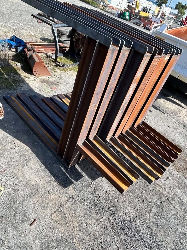 A batch of fabricated steel angle sections stacked in the yard, cut and marked ready for delivery.