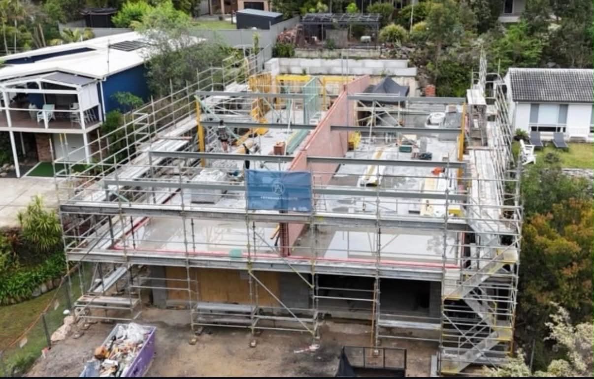 Overhead drone view of structural steel floor beams and columns erected across a two-storey home under construction.